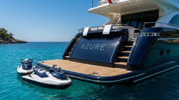 Azure yacht stern with jetskis in a turquoise bay